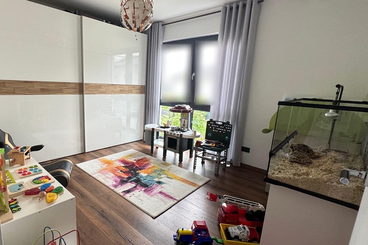 Blick in das helle Spielzimmer der Kindertagespflege Funty mit Spielküche, buntem Teppich und Terrarium